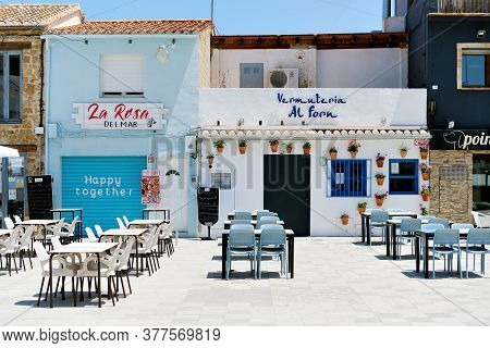 Denia, Spain - June 15, 2020: Sidewalk Cafe Empty Tables And Chairs On Charming Street Denia Square.