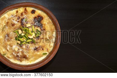 Traditional Arabic, Eastern Dessert Om Ali. Top View. Egyptian Bread Pudding In A Brown Bowl On Dark