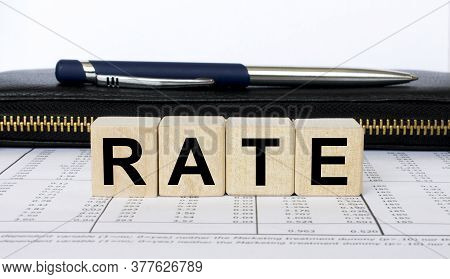 A Word Rate Written In A Wooden Cube With A Pen And Purse