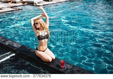 Young Hot Woman Resting At Swimpool. Sexy Beautiful Slim Woman In Black Swimsuit Hold Hands Up And S