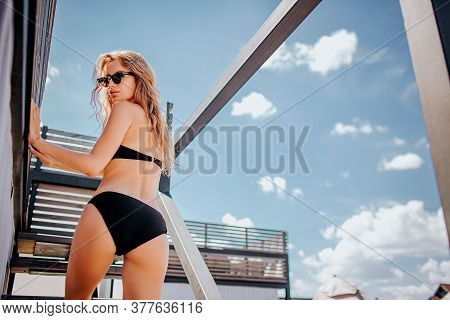 Young Hot Woman Resting Alone. Bakc Low View Of Slim Well-built Model In Black Swim Suit Posing On C