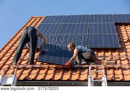 Ochojno, Poland - April 8, 2020: Workers Installing Solar Electric Panels On A House Roof In  Ochojn