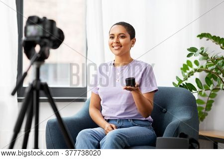 blogging, videoblog and people concept - happy smiling african american female video blogger with camera and smart speaker videoblogging at home