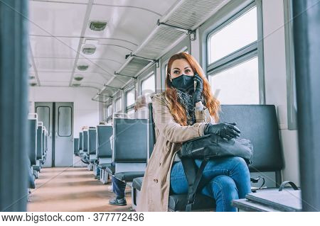 Red-haired Girl Speaks On The Phone, In A Train Carriage, With A Black Medical Mask.