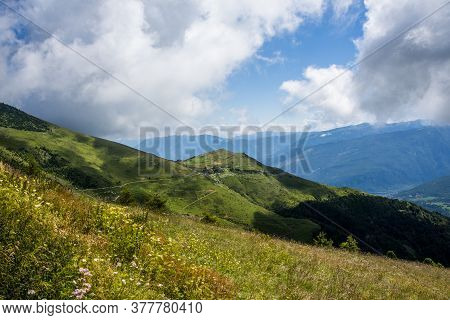 Beautiful View Of The Peaks Of Monte Baldo With Green Pastures The Woods And Clouds On The Blue Sky 