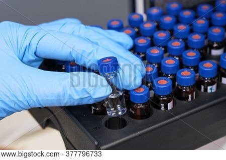Close Up Woman Hand In A Rubber Gloves Put Sample In A Glass Vial With Blue Cap Into The Autosampler