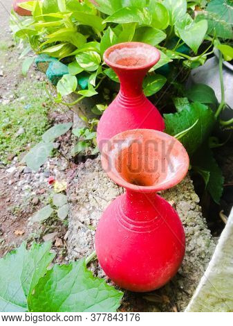 Two Earthen Pots Of Red Color Placed Side By Side To Each Other.the Pots Have A Big Mouth Followed B