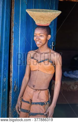 african woman  in a traditional leather costume with a basket on her head,  in a village in Botswana