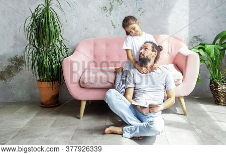 Cute Young Father Is Reading A Book To His Daughter. Happy Family Togetherness And Fatherhood. Littl