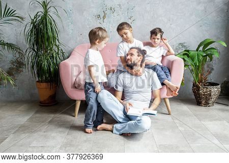 Young Father Is Reading A Book To His Children. Happy Family Togetherness And Fatherhood. Children S