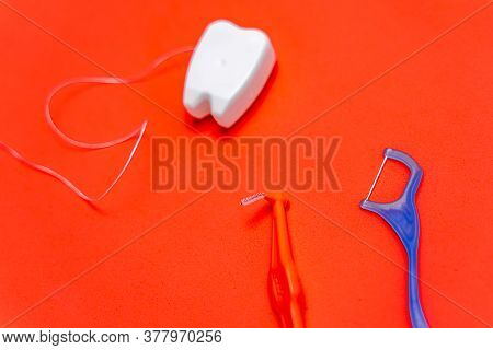 Different Types Of Dental Floss And Tooth Picks On Red Background. Dental Floss In Tooth Toy Shape.