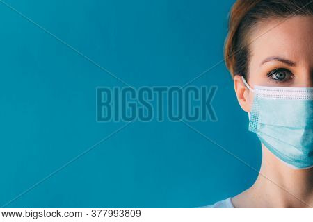 Close-up Half Face Of Young Woman In Medical Mask On Blue Background. Protection From The Coronaviru