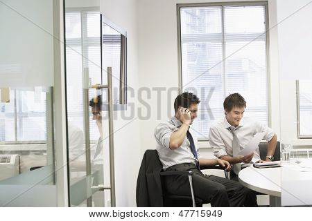 View through doorway to casual meeting between two relaxed young businessmen