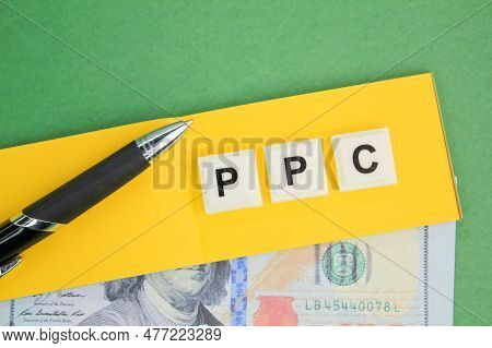 Pen, Paper And Money With The Letters Ppc Or The Word Pay Per Click. Paid Marketing Concept Or Pay P