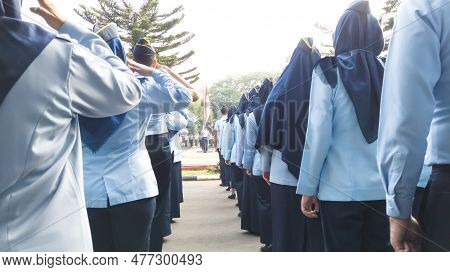 Rear View Of Cadets In Uniform Saluting To The Indonesian's National Flag, Merah Putih, On The Morni