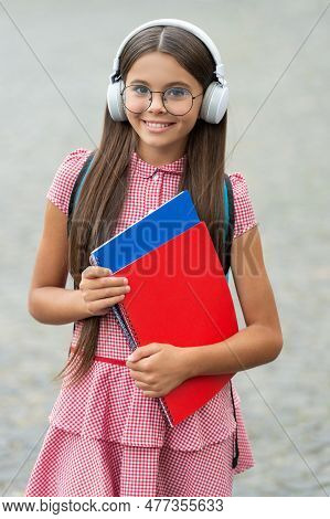 Teen Girl Has Estudy In Headphones Hold Notebook. Teen Girl Has Estudy Outdoor.