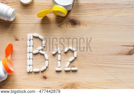 B12 Vitamin. Green Pills Forming Shape To B12 Alphabet On Wooden Background, Copy Space, Top View.