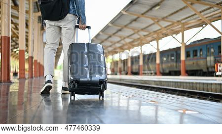 Cropped Image Of A Male Commuter Walking Along The Platform With His Suitcase