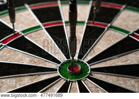 Three Darts Hit The Dartboard. Lucky - One Of The Darts Hits The Bulls Eye. The Concept Of Winning A