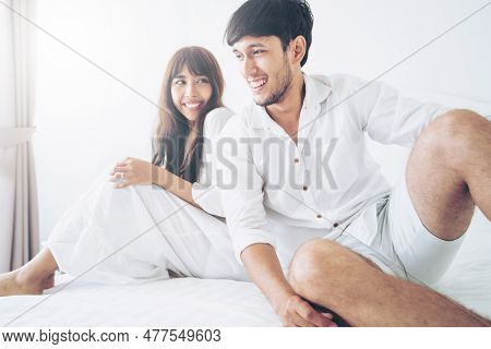 Happy Young Couple Relaxing In Home Bedroom After Waking Up In The Morning.