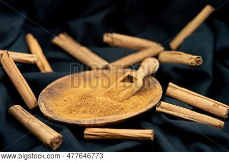 Dried Cinnamon Sticks And Powder On Olive Wood
