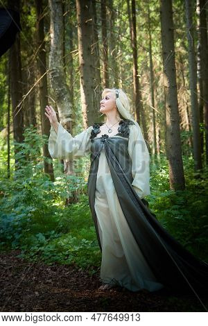 Adult Mature Woman 40-60 In A Green Long Fairy Dress In Forest. Photo Shoot In Style Of Dryad And Qu