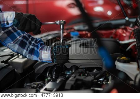 Female Auto Mechanic Unscrewing A Nut To Replace A Car Spark Plug.