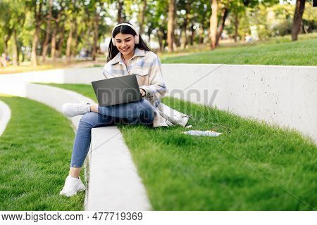 Technology And Studentship Concept. Cheerful Lady Student Using Laptop Computer And Wearing Headphon