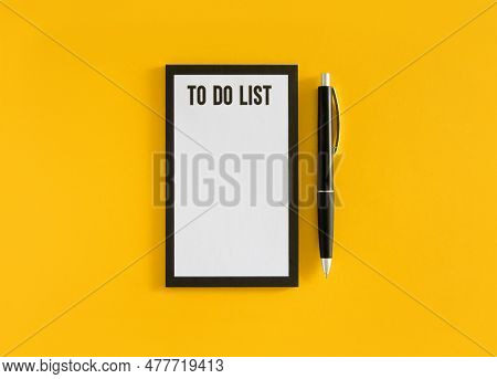 White Sheet With To Do List Phrase And Black Pen On Yellow Background. Stock Photo.
