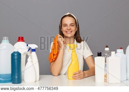 Attractive Smiling Positive Woman Posing At Workplace With Cleaning Detergents Isolated Over Gray Ba