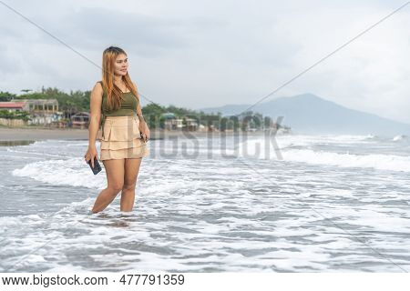 Beautiful Young Filipina Woman,playfully Paddling In The Shallow Waves Of The Long Sandy Beach At Ib