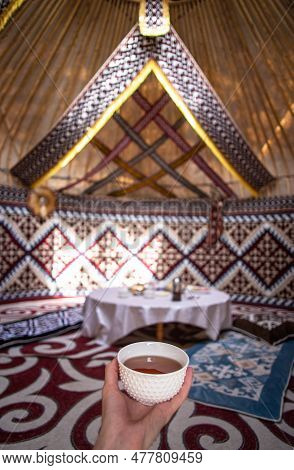 A Cup Of Tea In A Man's Hand Behind A Dastarkhan In The Kazakh National Yurt.