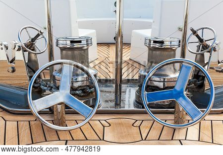The Bow Of The Yacht With Teak Deck, With Anchor Stops, Part Of The Anchor Chain, Winch For Tighteni