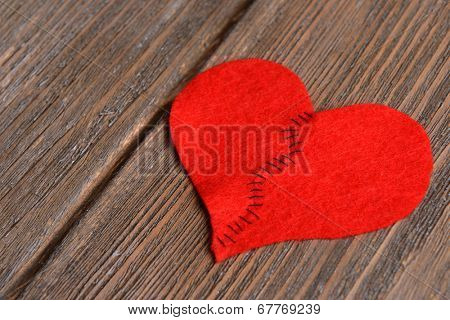 Broken heart and thread on wooden background
