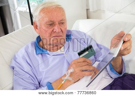 Man in his sickbed uses a credit card payment over the internet