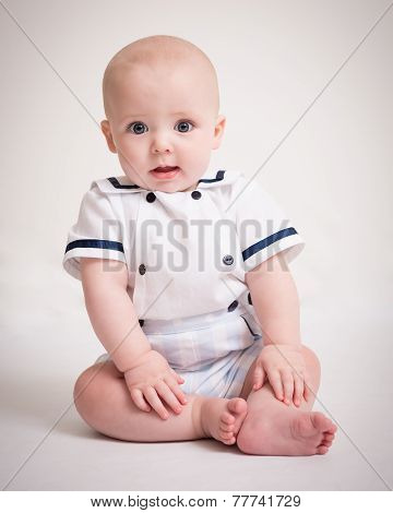 Baby Boy Sitting On Floor In Sailor Suit