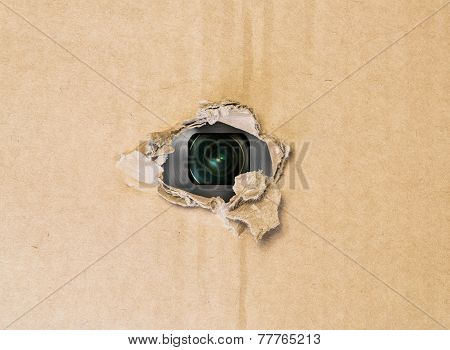 Hidden camera in torn hole in cardboard paper