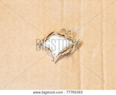 Torn hole in cardboard paper