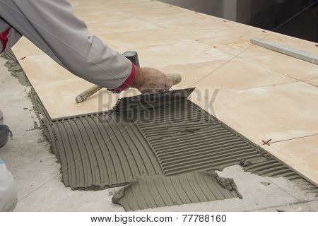 Home improvement, renovation - construction worker tiler is tiling, ceramic tile floor adhesive, tro
