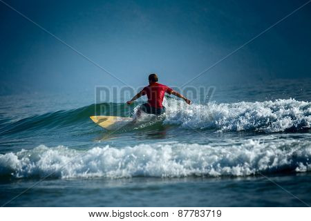 Surfer riding the wave on the short board at sunny day