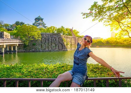 Tourist enjoys in front of Osaka Castle and Gokurakubashi Bridge at sunset. Freedom and asia travel concept. Defocused background. Osaka Castle is one of the most famous landmarks in japan. Light shot