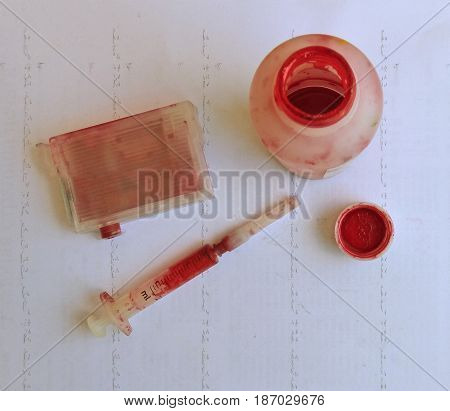 Process of ink cartridge refill - toner in open bottle and syringe. On dirty paper. Jet printer maintenance.