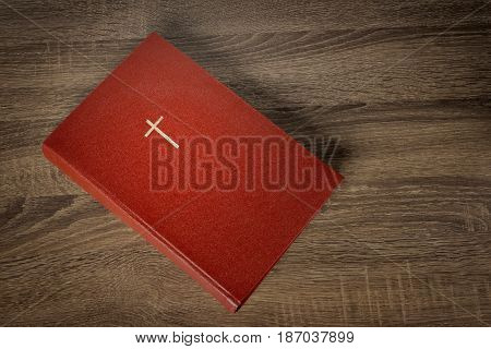 Red bible with cross on cover, wooden table background