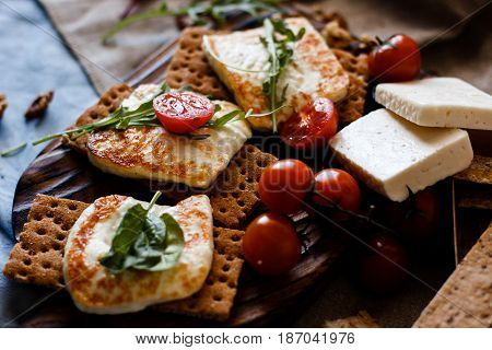 Grilled homemade halloumi cheese with fresh green herbs over wooden background, top view, close-up.