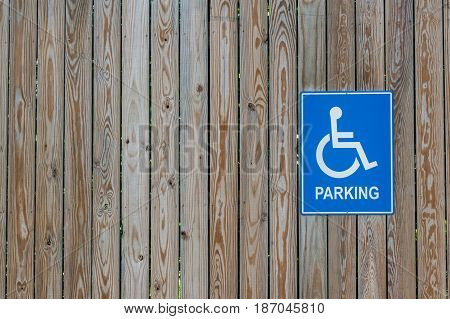 Handicapped parking sign on a wooden fence.