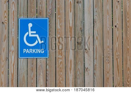 Handicapped parking sign on a wooden fence.