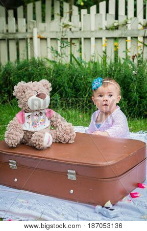 Baby sitting near suitcase in the summer garden