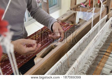 Old asia women demonstrate to procedure of making Thai Silk weaving in small weaving mill