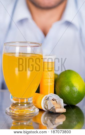 Lemon, pills of vitamin C and a glass of vitamin C dissolved over the table.