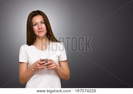 Beautiful attractive casual young woman talking through the headphones on her mobile phone. Studio shot on gray background.